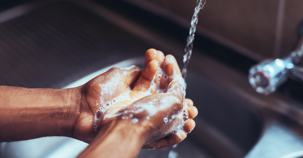 A close-up of hands being washed with soap under running water, emphasizing hygiene as a preventive measure against the common cold and flu.