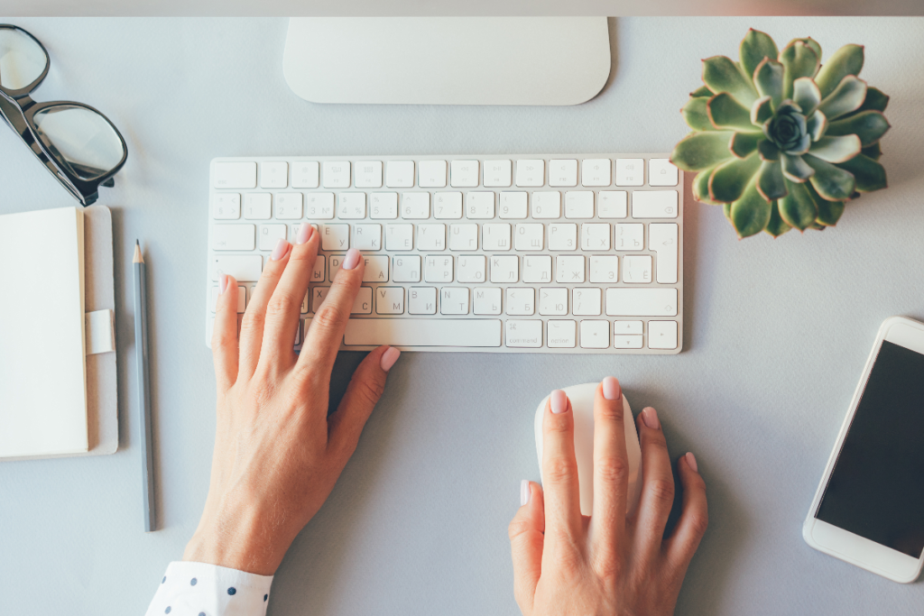 A tidy desk with a keyboard, notebook, pencil, smartphone, and a small succulent plant, showcasing an organized workspace.