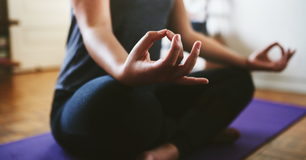 A woman practicing mindfulness meditation on a yoga mat to reduce stress and support thyroid health.