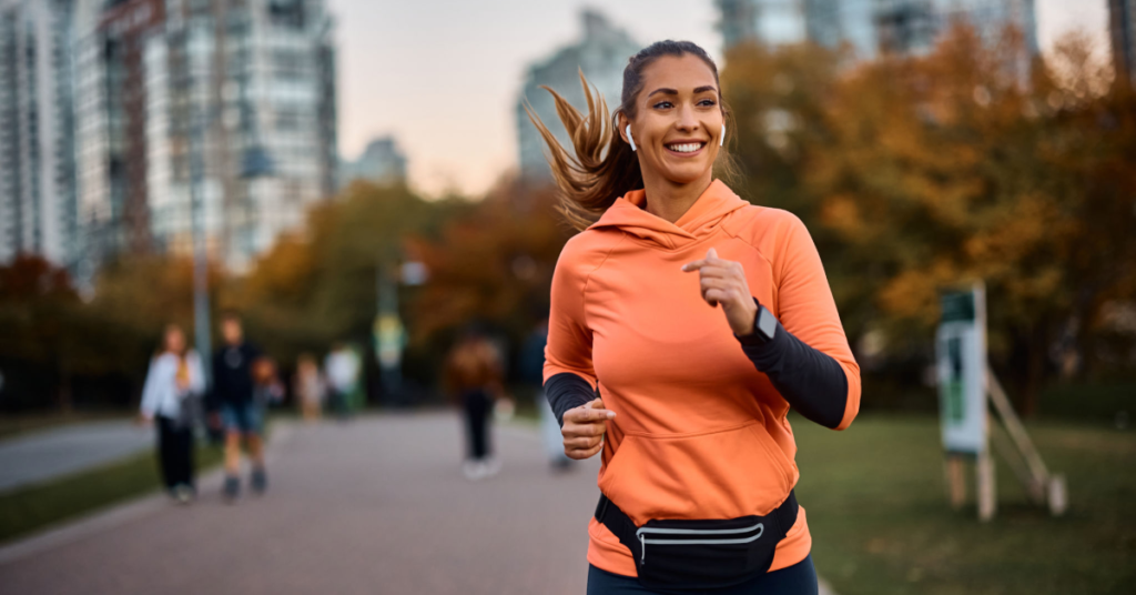 Smiling woman jogging in a park, symbolizing vitality and an active lifestyle.