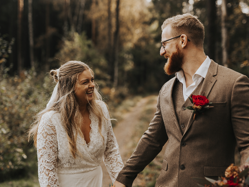 A joyful couple sharing a laugh outdoors, symbolizing the positivity and happiness of an emotionally strong husband in a healthy marriage.