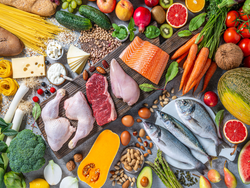 A variety of heart-healthy foods including salmon, fresh vegetables, fruits, nuts, and whole grains.