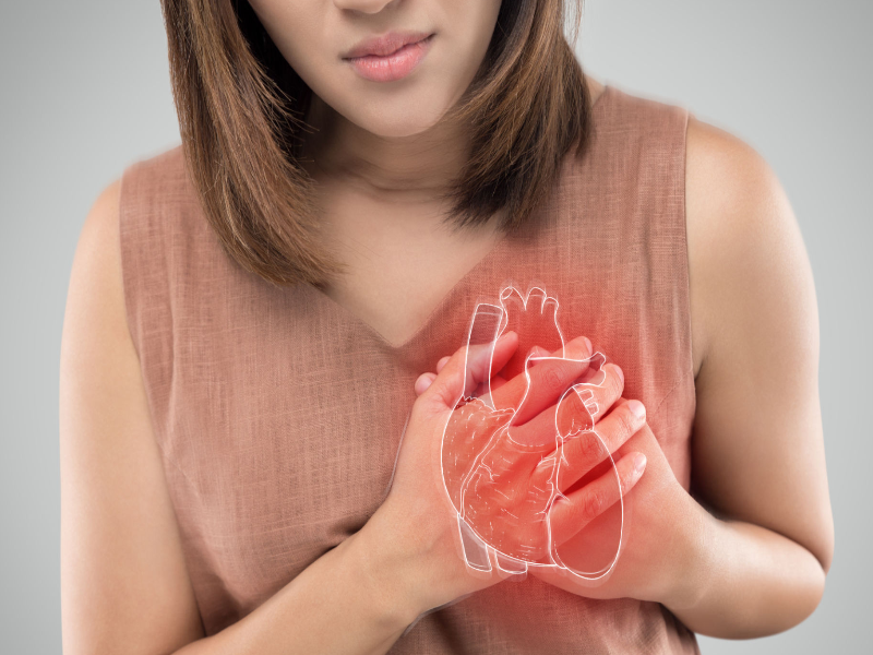 A woman holding her chest with a glowing illustration of a heart, depicting signs of heart disease in women.