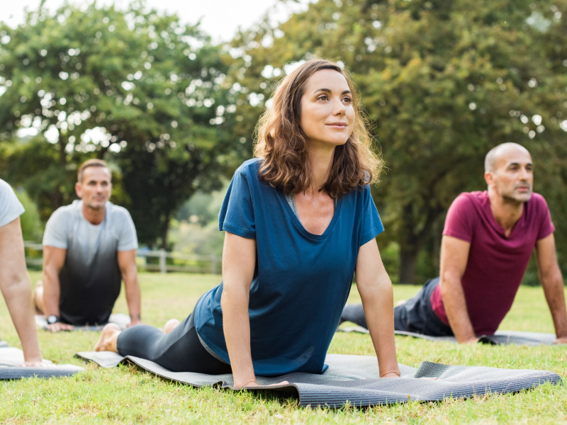 Women practicing yoga outdoors as part of stress management for heart health.