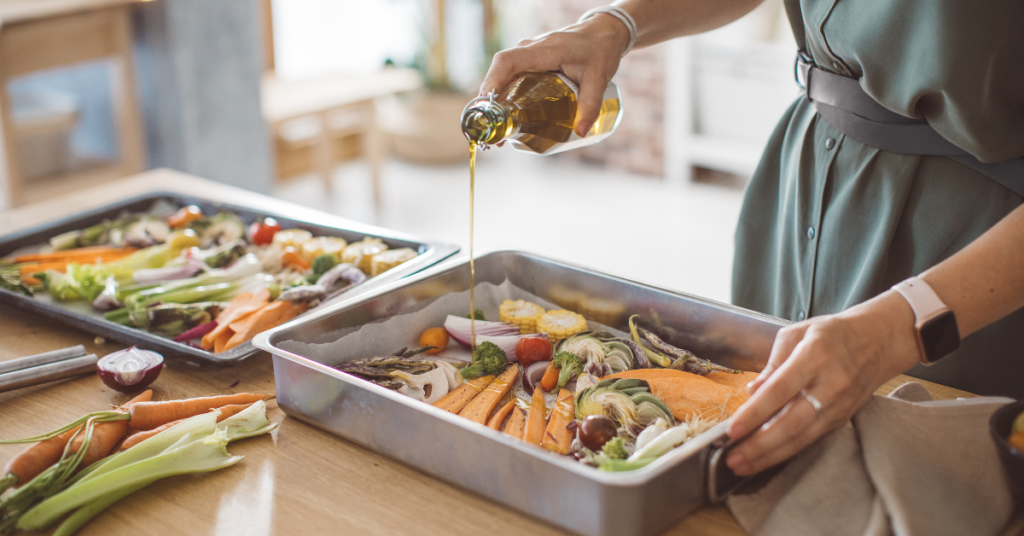 A person preparing a tray of colorful vegetables with olive oil, highlighting the connection between balanced nutrition and liver health.