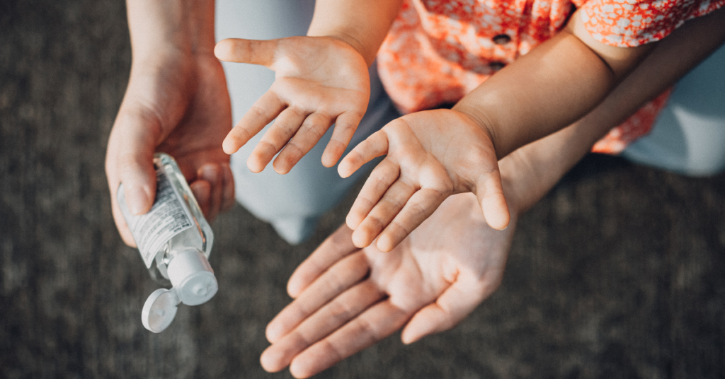 Parent applying hand sanitizer to a child's hands, illustrating norovirus prevention and symptoms awareness through proper hygiene.