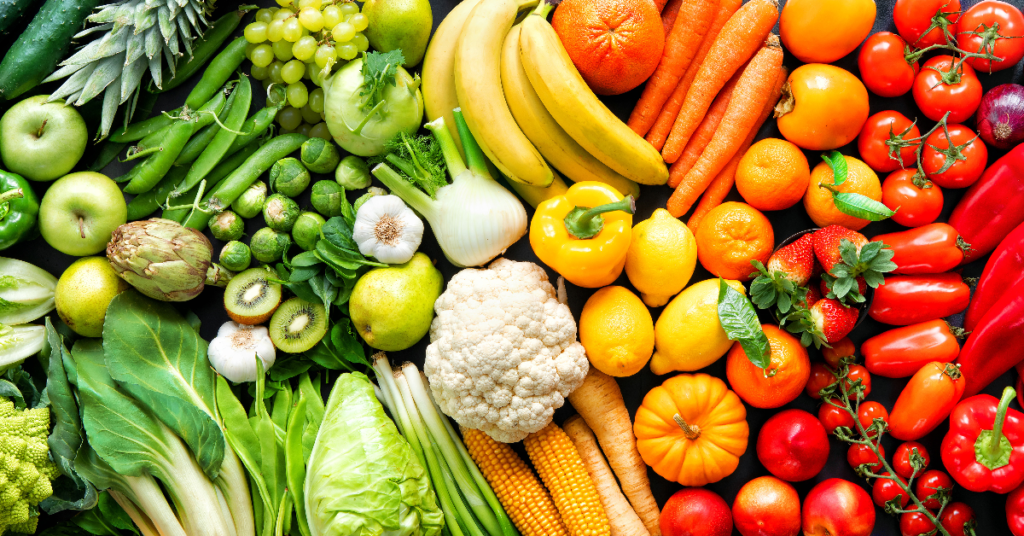 A colorful assortment of fresh fruits and vegetables, including spinach, citrus fruits, carrots, bell peppers, and leafy greens, rich in iron and vitamins to naturally combat anemia in women.