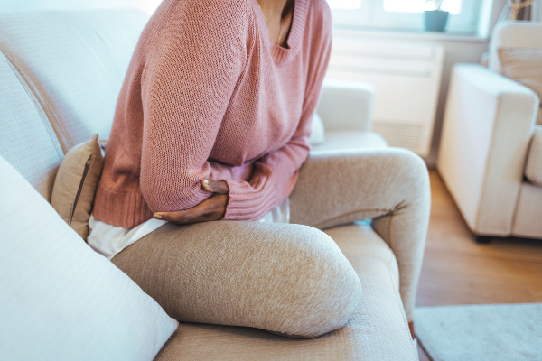 A person clutching their stomach in pain, illustrating common symptoms of norovirus.